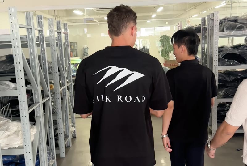 A Silk Road team member in a Silk Road tee walking through a supplier's stockroom with the supplier