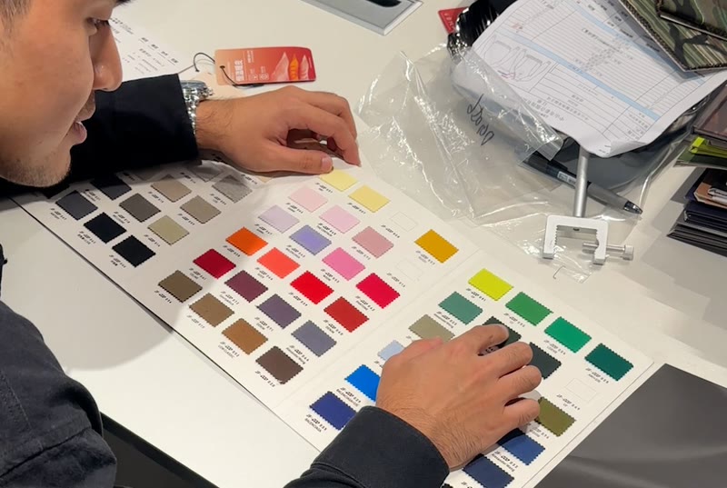 Going through a garment spec sheet with fabric colour swatches and a hangtag on the table