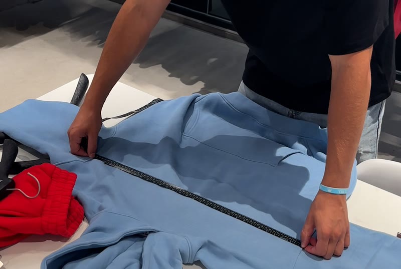 A hoodie laid flat and measured with a tape during a quality check